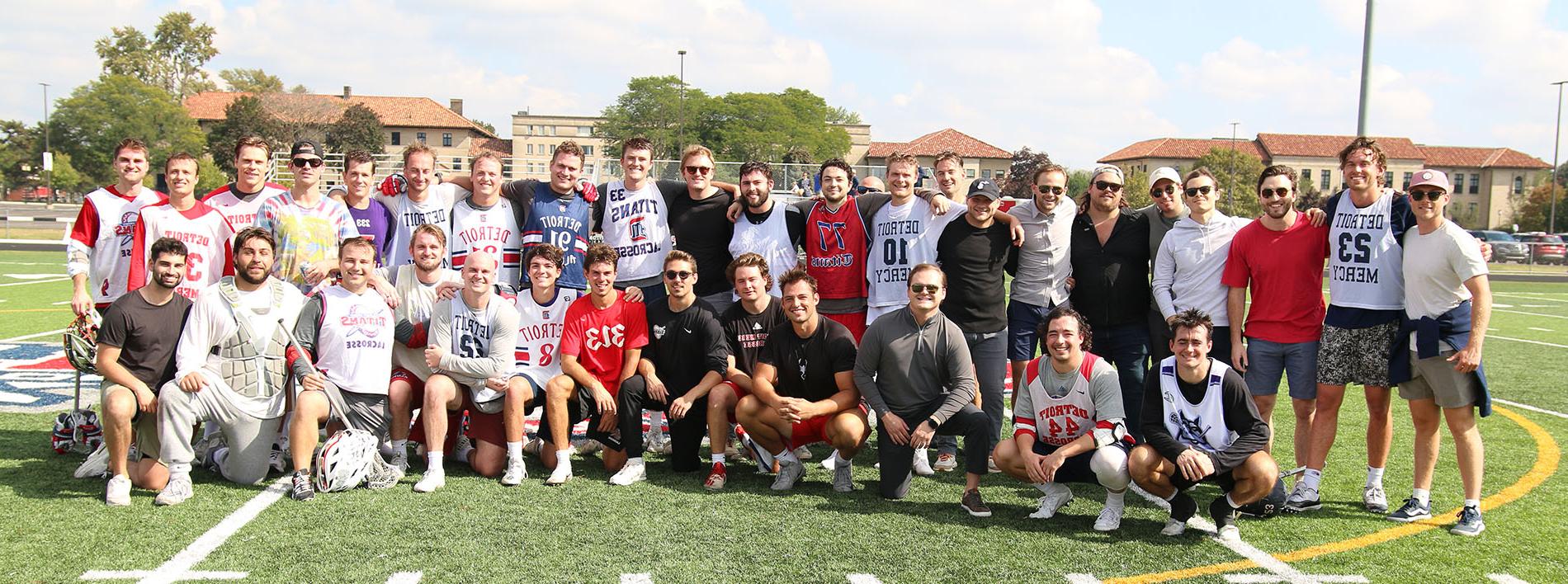 Detroit Mercy men's lacrosse student-athletes and alumni pose for a team photo on Titan Field after the alumni game.